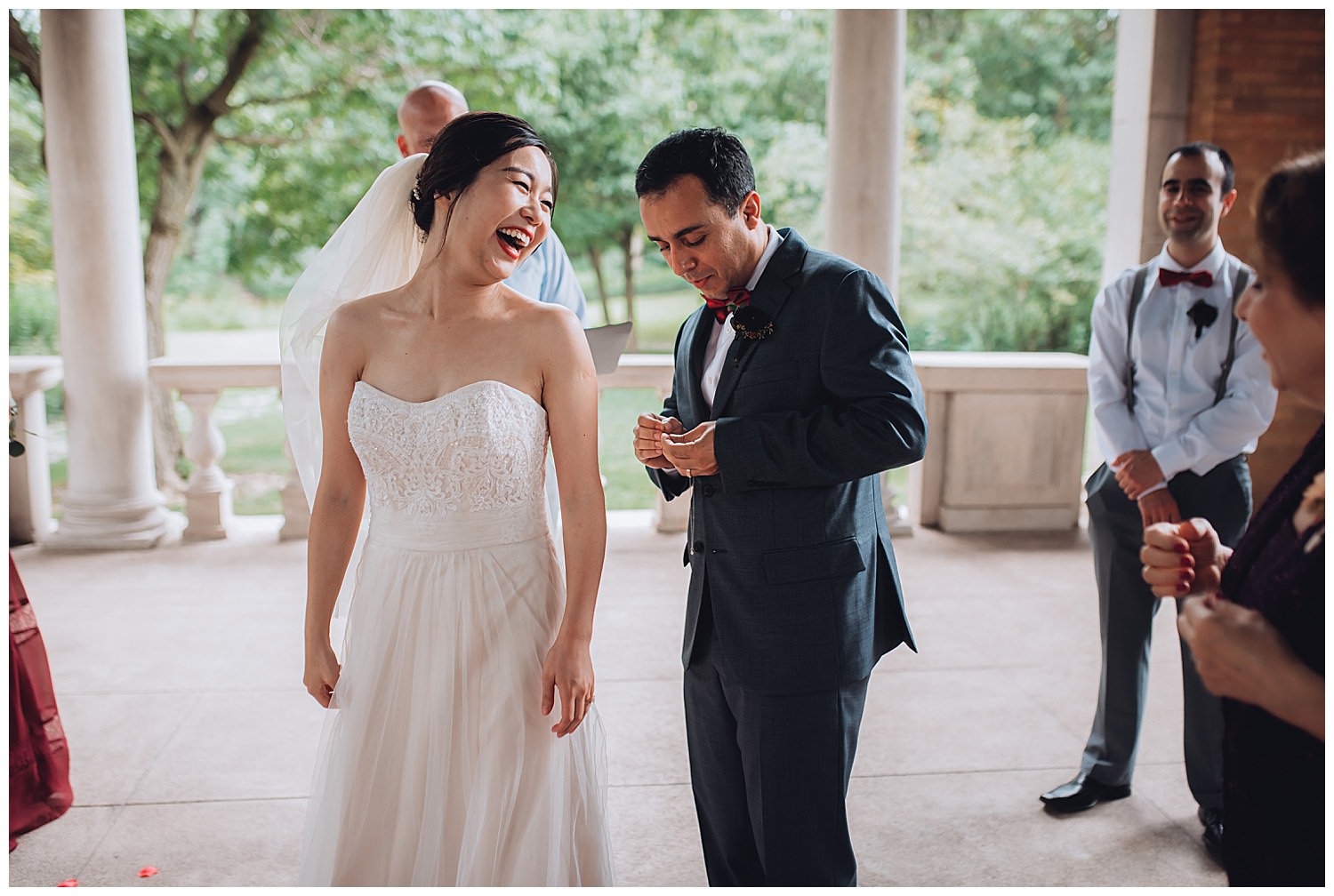 Columbus Park Refectory Wedding, groom trying to open a necklasse while bride laughing during ceremony