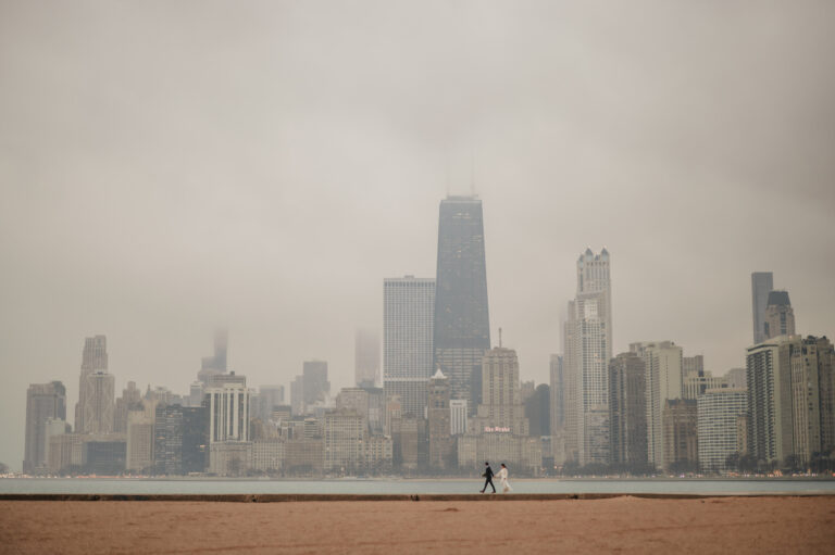 Rainy-Chicago-Elopement-The-Adamkovi- COuple running on north avenue beach with Chicago skyline behind them